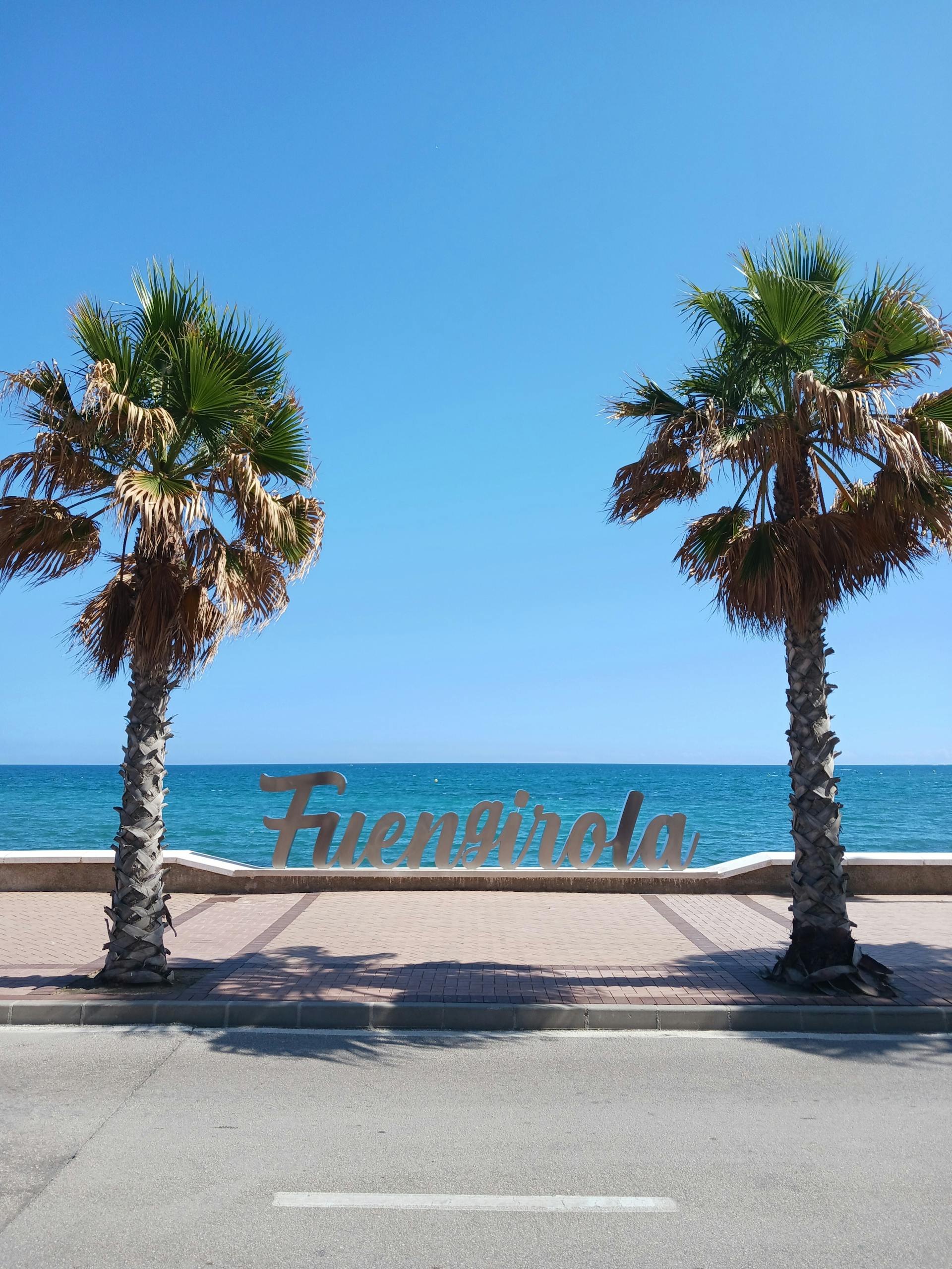 Fuengirola seafront sign with palms and Mediterranean water
