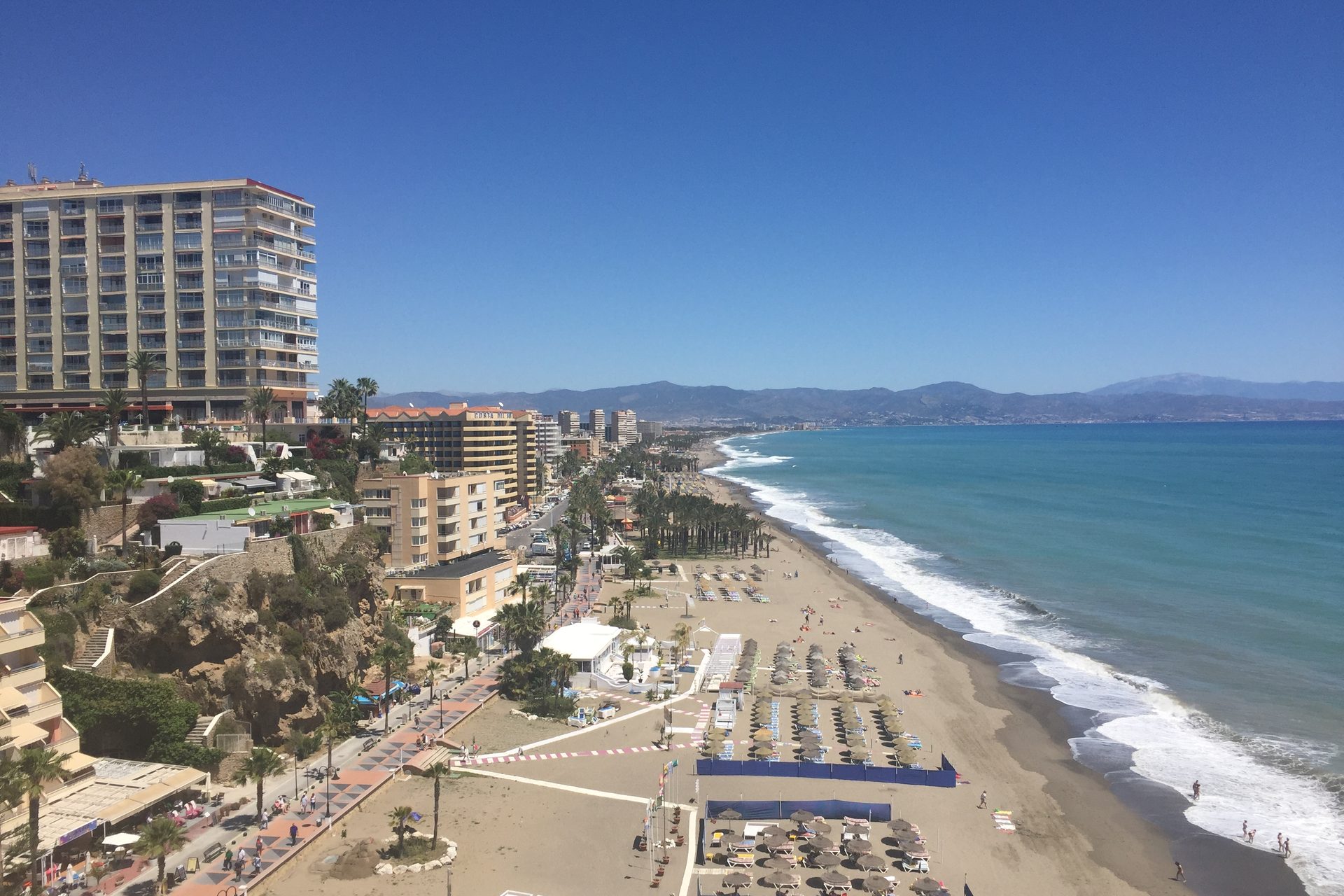 Het strand van Torremolinos van bovenaf gezien, met de boulevard, palmen en appartementengebouwen langs de kust