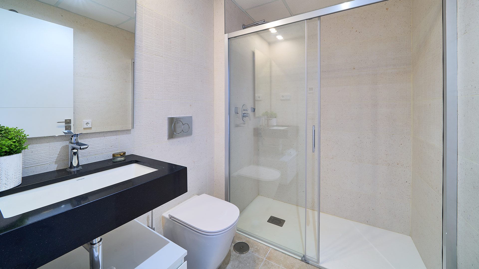 Badkamer met een lang hangend wastafelmeubel, een hangend toilet en een glazen inloopdouche