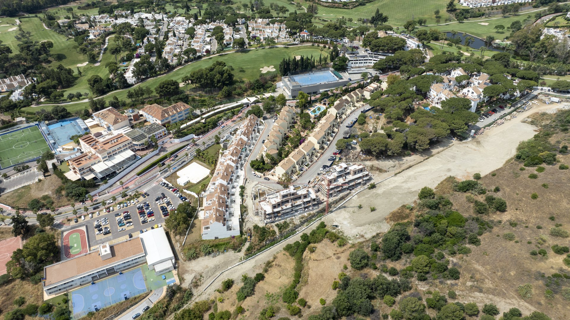Aerial view of Los Olivos Residences under construction in Marbella's Golf Valley, with the coastline beyond