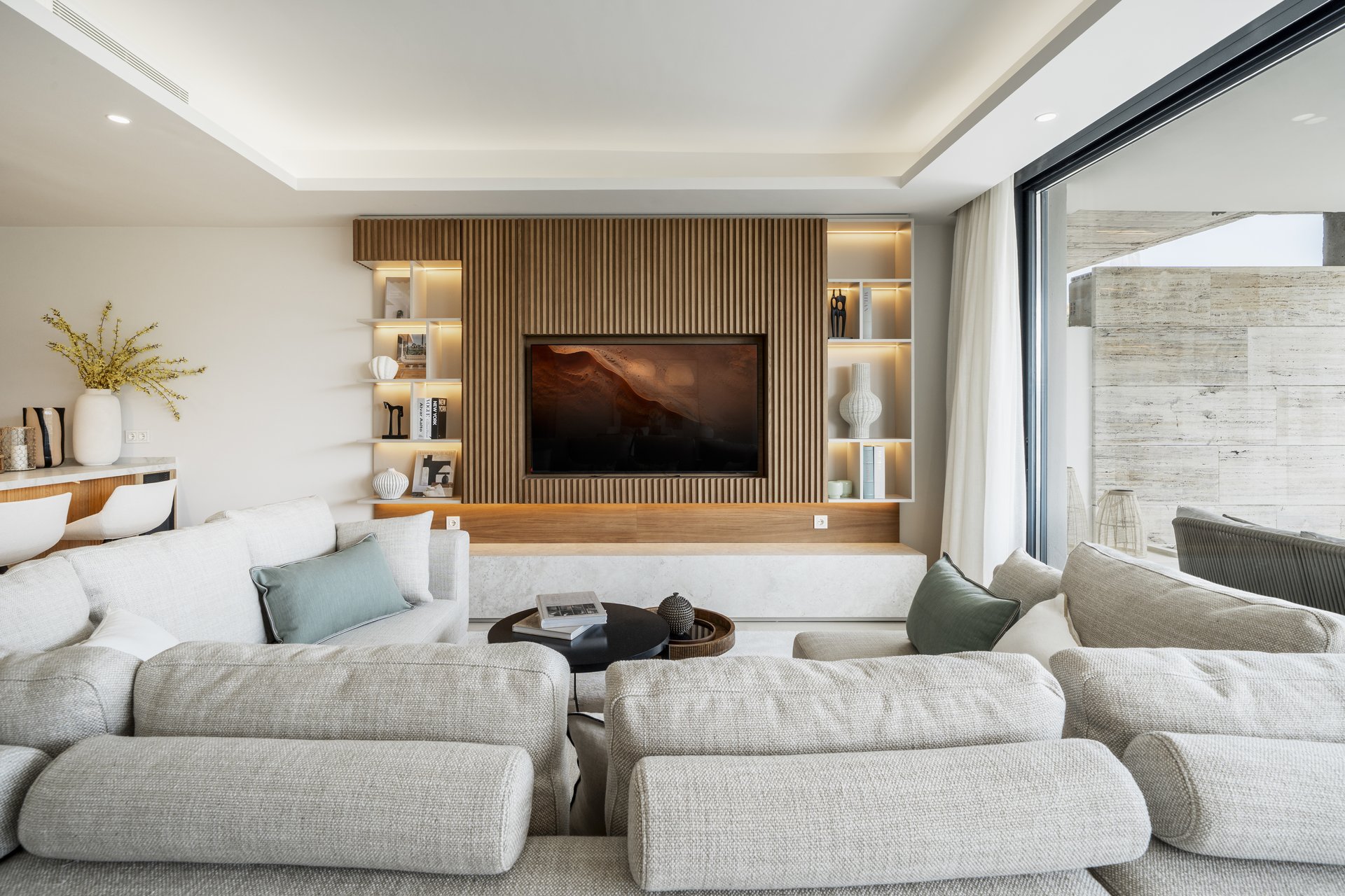 Show apartment living room with wood-panelled media wall and neutral furnishings