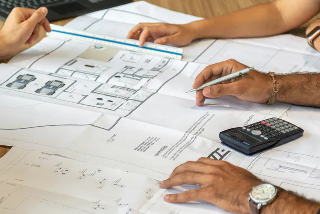 Architectural plans and cost calculations being reviewed for a new development